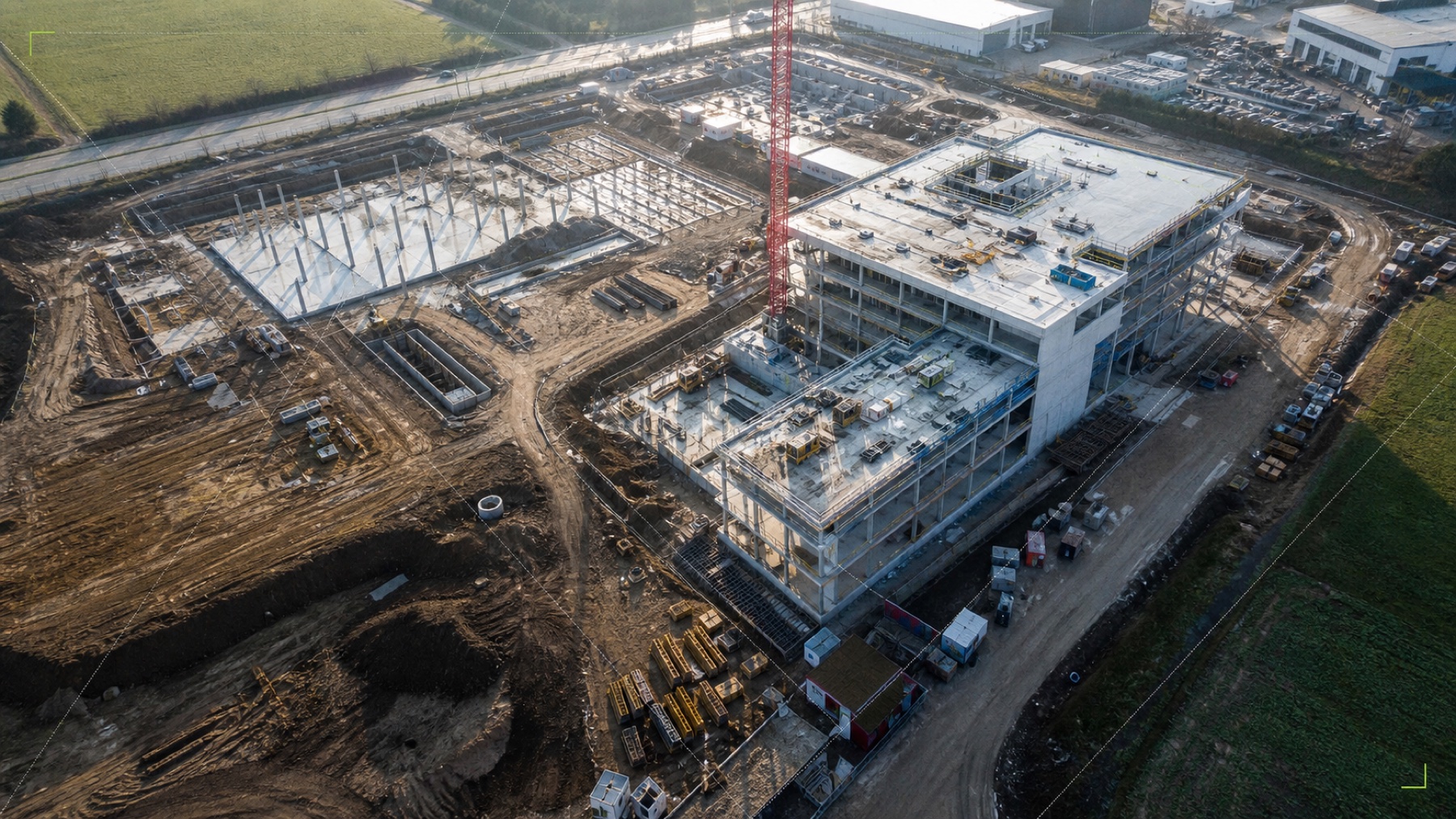 Realistische Drohnenansicht einer Baustelle mit mehreren sichtbaren Bauphasen